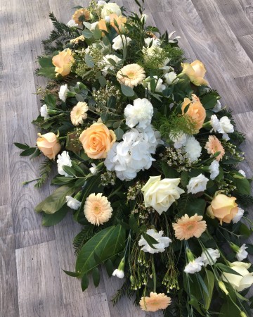 ivory and peach casket spray - funeral tribute design - ivory roses, carnations, hydrangea and waxflowers with peach germini and mixed foliages 