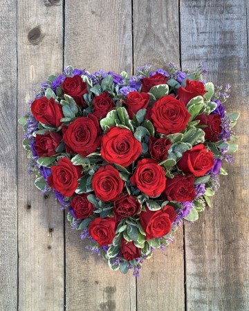 full heart of red oses with a purple lisianthus boarder and mixed foliage