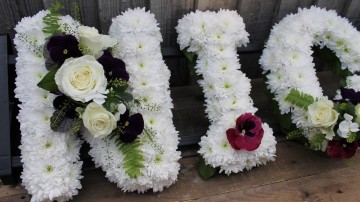 Name Funeral Tribute based in white chrysanthemum with foliage edge, white rose and cut Pansy flowers