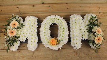 Mom funera tribute based in chrysanthemum with peach Germini and ivory sprays 
