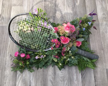 Tennis Racket on pillow of mixed pink flowers 