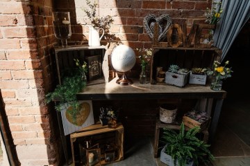 entrance tables at shustoke farm barns decorated with crates plants flowers