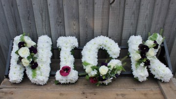 Name Funeral Tribute based in white chrysanthemum with foliage edge, white rose and cut Pansy flowers 