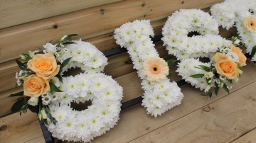 Sister funeral tribute foliage edge based in white chrysanthemum with peach rose sprays