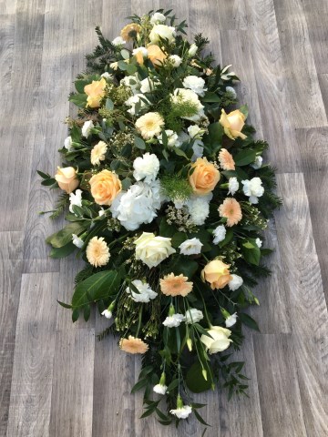 ivory and peach casket spray - funeral tribute design - ivory roses, carnations, hydrangea and waxflowers with peach germini and mixed foliages 